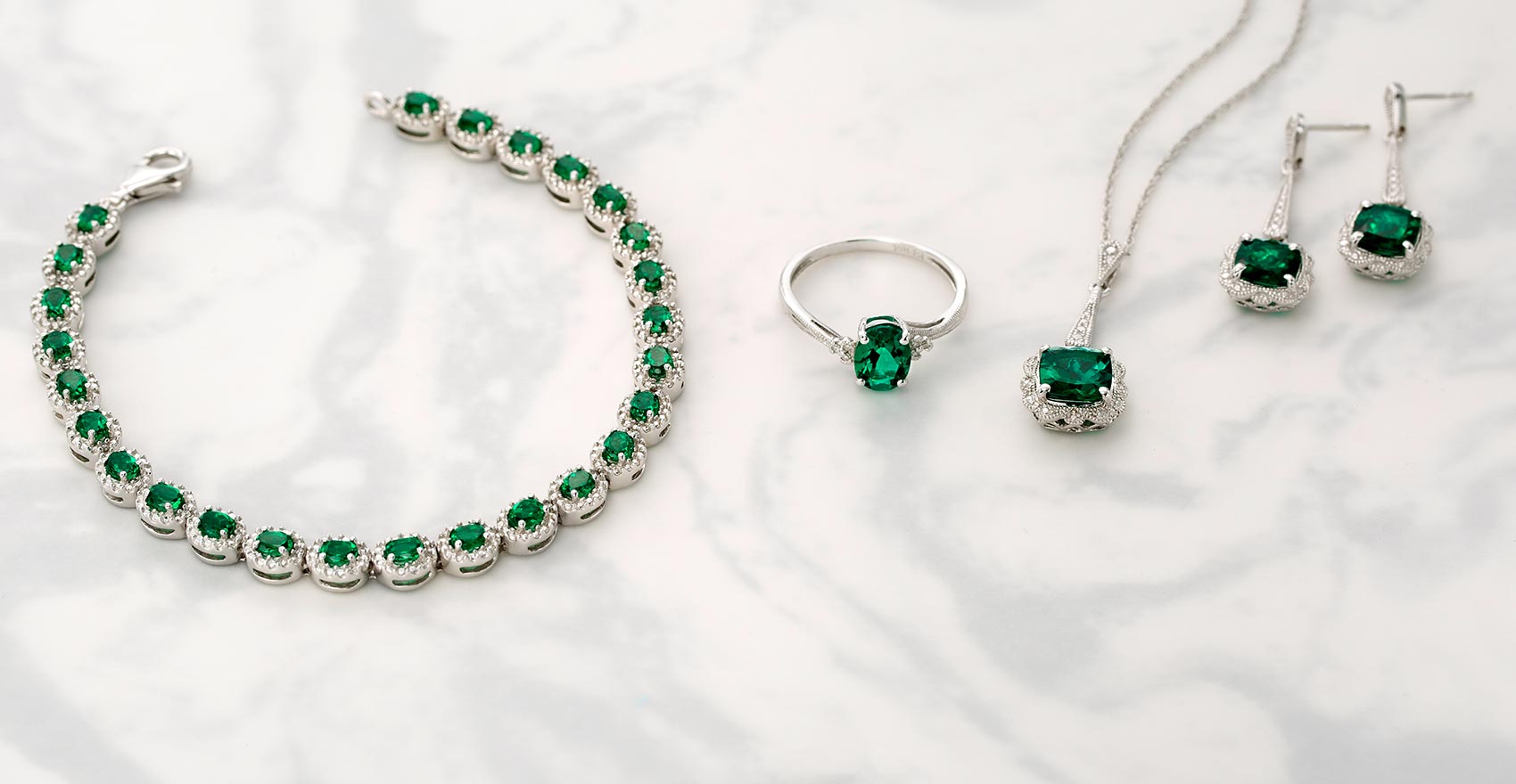 Matching jade jewelry set: necklace, earrings, ring and bracelet on a marble background